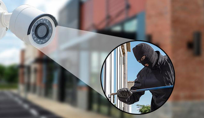 Outdoor commercial security camera detecting a masked intruder attempting forced entry