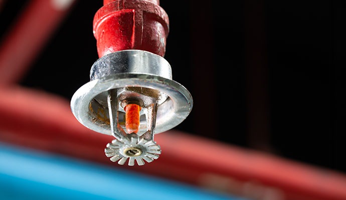 Chrome fire sprinkler with orange bulb on red pipe