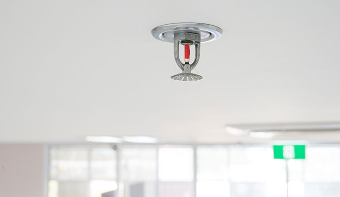 Chrome fire sprinkler with red bulb on white ceiling