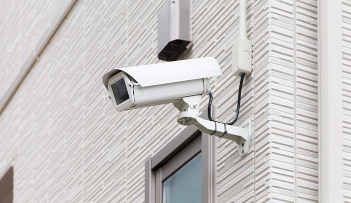 White commercial security camera mounted on an exterior building wall