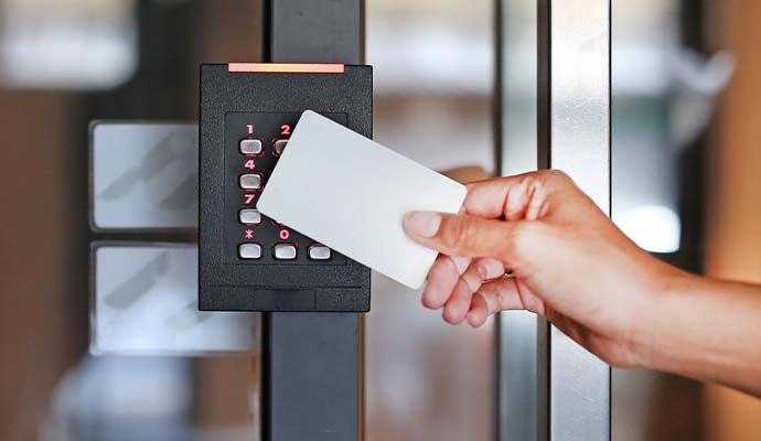 Person swiping a keycard badge on an electronic access control keypad reader