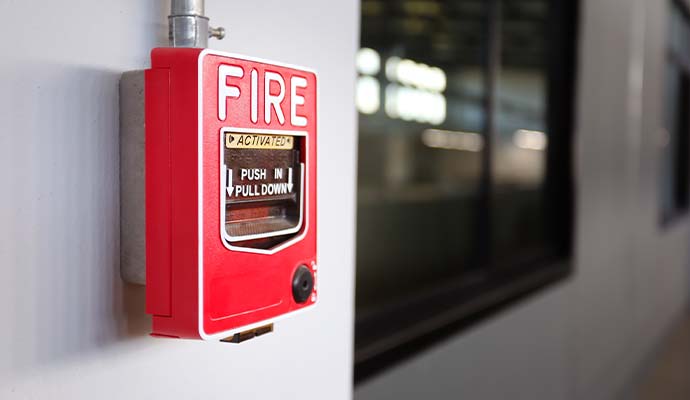 Red commercial manual fire alarm pull station mounted on a wall