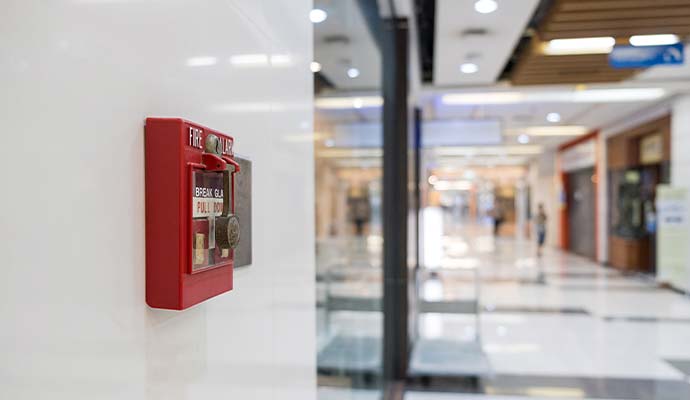 Commercial fire alarm station mounted on a wall in a shopping mall hallway