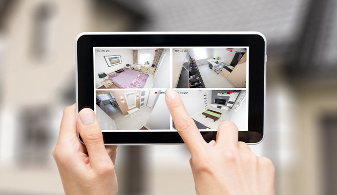 Hands holding tablet with home security camera feeds