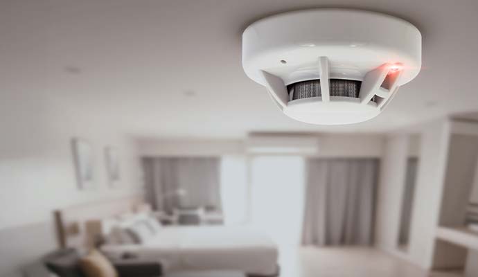 Ceiling smoke detector with an active indicator light in a residential bedroom