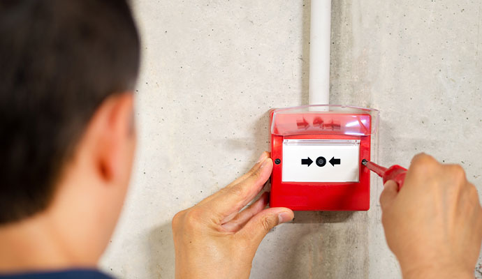 Technician installing red fire alarm call point