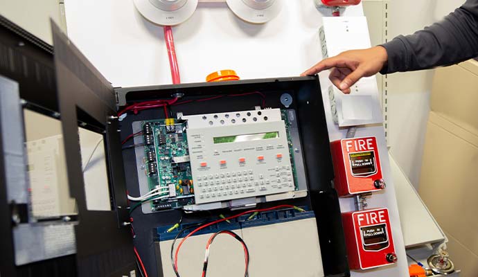 Technician configuring and testing a commercial fire alarm control panel keypad