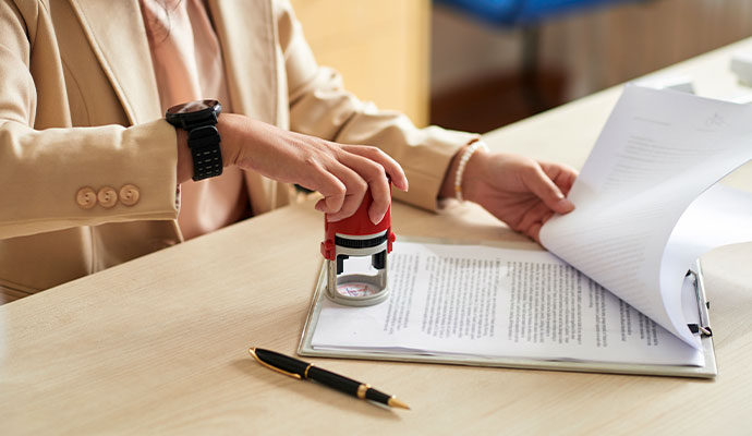 Notary public applying an official notary stamp to a legal document on a desk