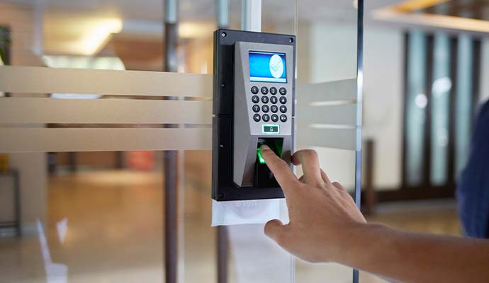A person using biometric fingerprint scanner mounted on a glass office door