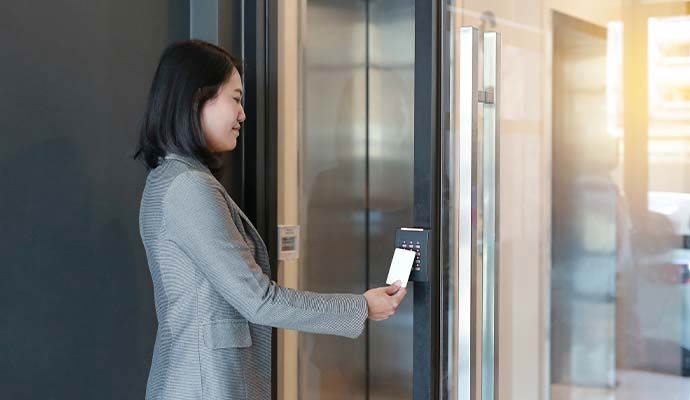 Businesswoman scanning access card at electronic door keypad
