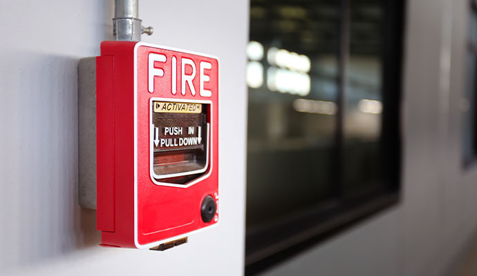 Red commercial fire alarm pull station on a wall