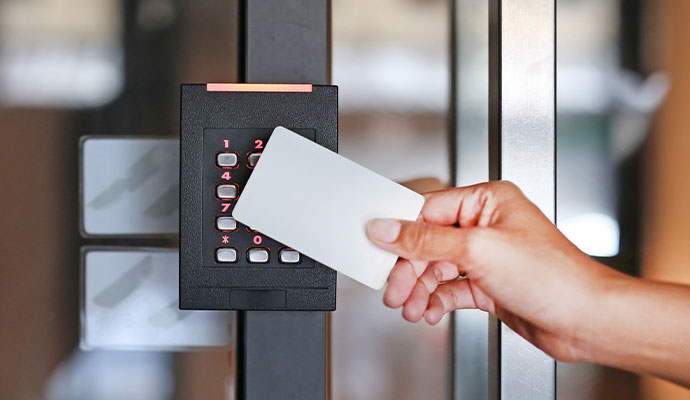 Hand holding a key card against a door access reader