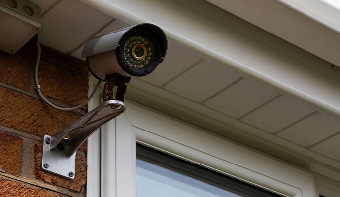 Silver outdoor bullet security camera on a brick wall.