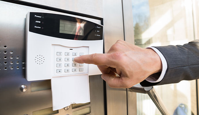 Person entering a code on a wall-mounted security alarm keypad.