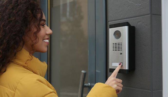 Person pressing a video doorbell button at a building entrance