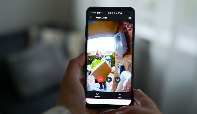Person viewing a front door camera feed of a delivery on a smartphone