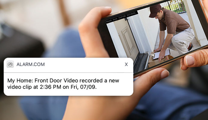 Person viewing a front door video clip alert on a smartphone.
