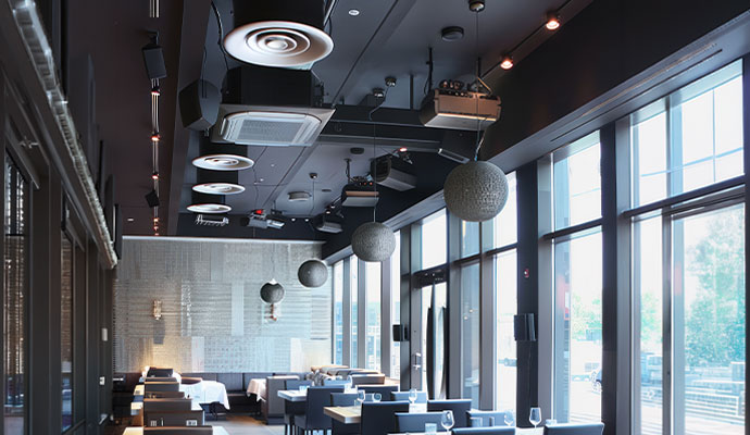 Upscale restaurant dining room with ceiling-mounted speakers.