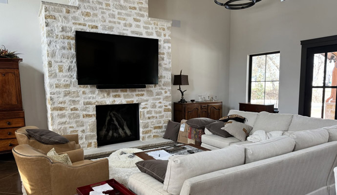 Living room with smart TV mounted above a stone fireplace