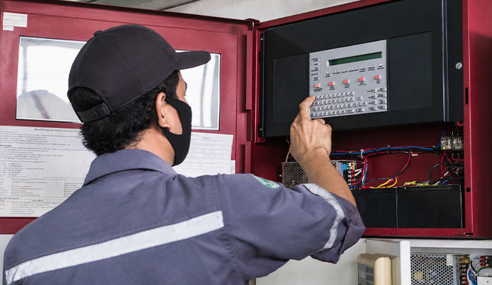 Technician checking a fire alarm control panel