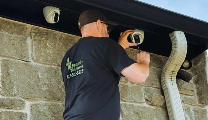 Technician installing an outdoor security camera under a roof