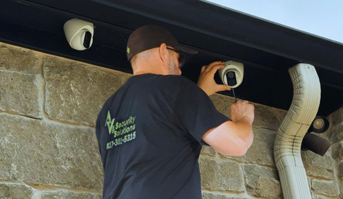 Technician installing an outdoor dome security camera on a stone home