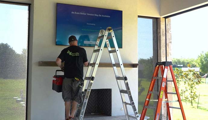 Technician installing TV display above a fireplace