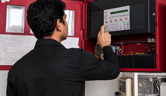 Technician working on fire alarm control panel