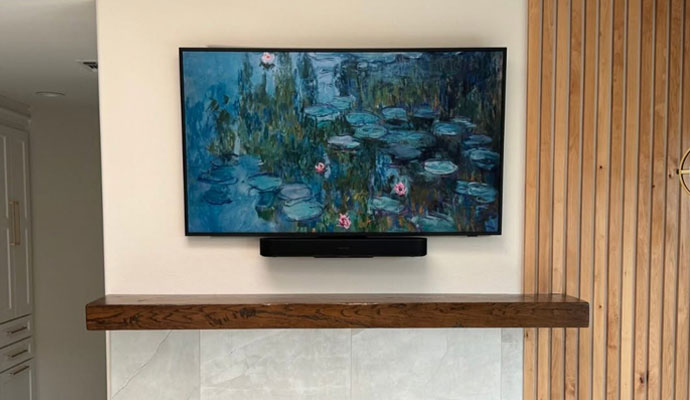 Wall-mounted TV in art mode with a soundbar above a fireplace mantel.